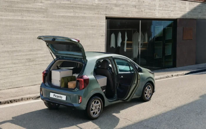 A Kia Picanto hatchback car with all doors open near a building