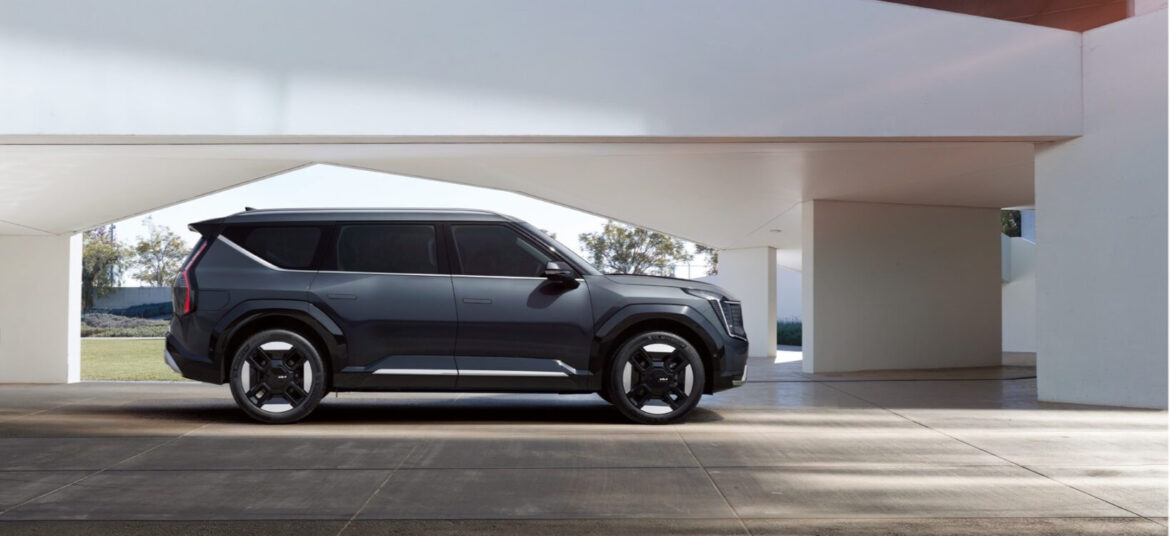 An aurora black pearl color kia EV9 electric SUV parked in a parking area inside a building