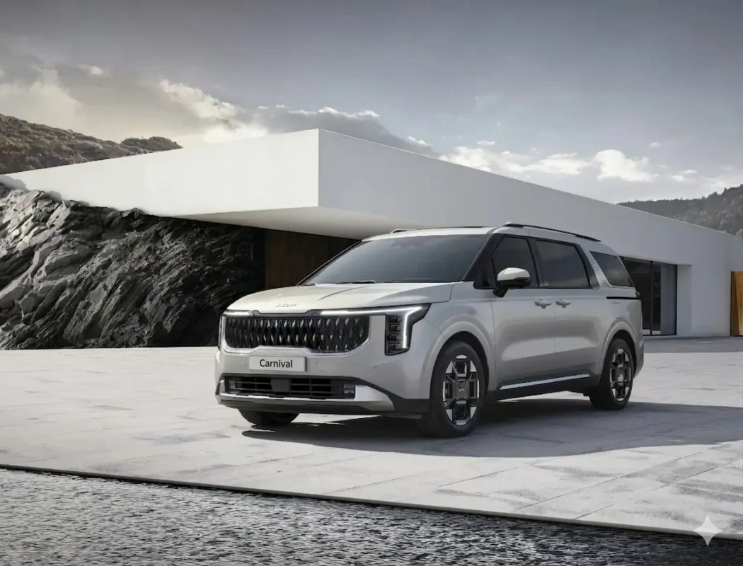 An Ivory Silver color Kia Carnival MPV parked infront of a minimalistic building
