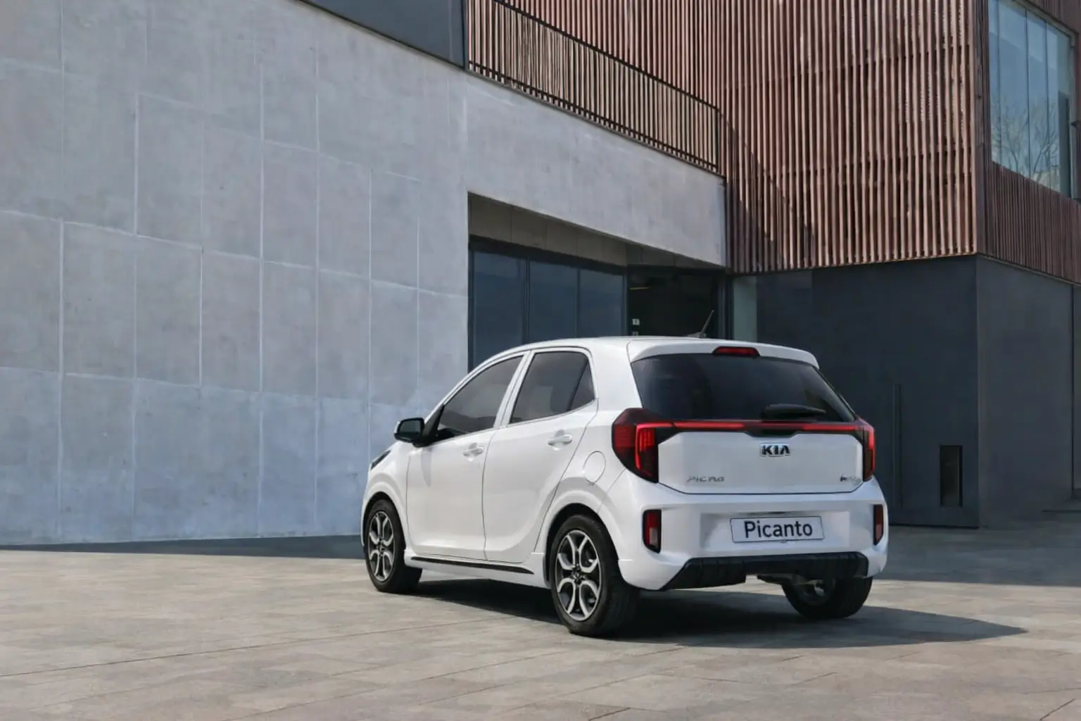 A white coor kia picanto hatchback car parked in front of a building